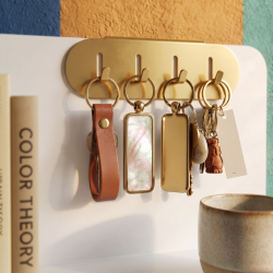 Porte-clés en acier Perle, coloris doré, sur une étagère Aventurine.